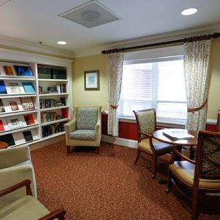A cozy reading area with a bookshelf, chairs, and a table by the window.
