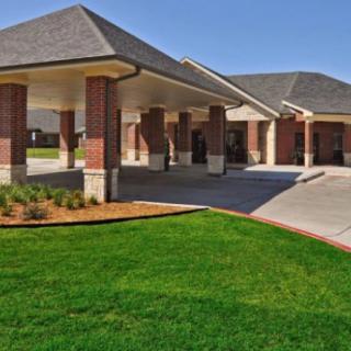 A modern brick building with a covered driveway and well-maintained lawn.