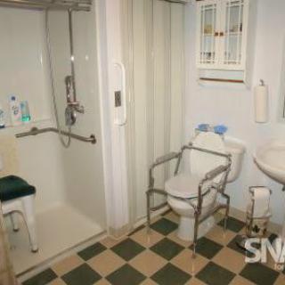 An accessible bathroom with a shower, safety rails, and assistive equipment for ease of use.