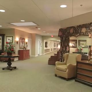 A well-decorated lobby area with armchairs, artwork on the walls, and a long hallway.