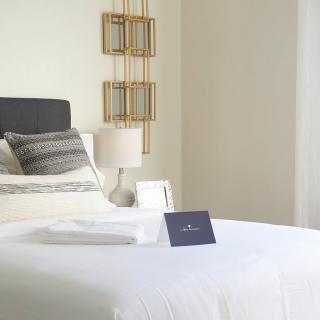 A minimalist bedroom with a neatly made bed, adorned with modern decor and soft lighting.