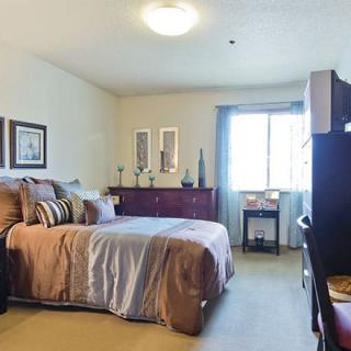 A cozy bedroom with neatly arranged furniture and a window letting in natural light.