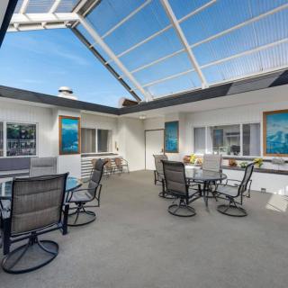 A bright patio area with tables and chairs under a glass ceiling.