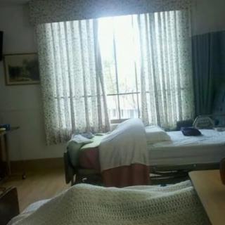 A dimly lit hospital room with beds and closed curtains.