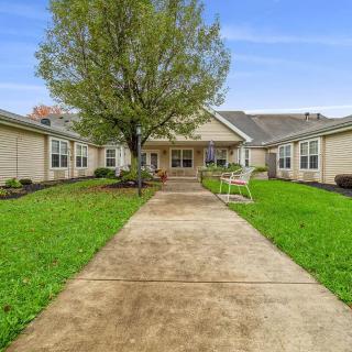 A single-story house with a large front lawn and a pathway leading to the entrance.