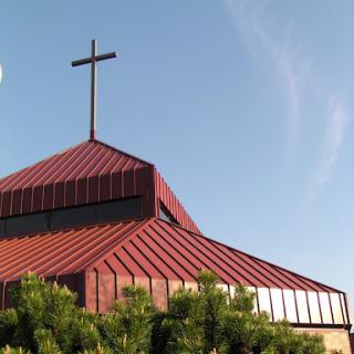 A church building with a distinctive red roof and a prominent cross.