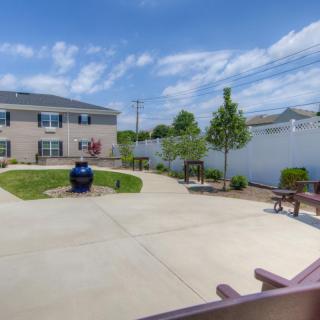 A residential backyard featuring a garden area with benches and young trees, enclosed by a white fence.