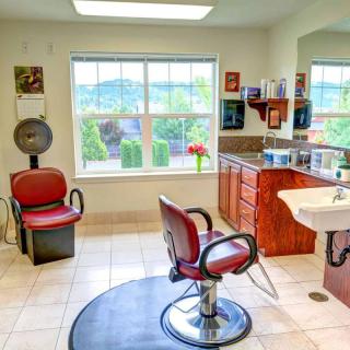 A bright and spacious hair salon with red barber chairs and a picturesque view from the window.