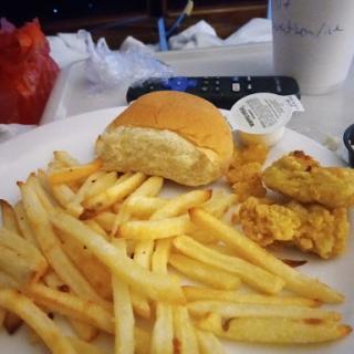 A plate featuring fries, a bun, and a piece of fried chicken.