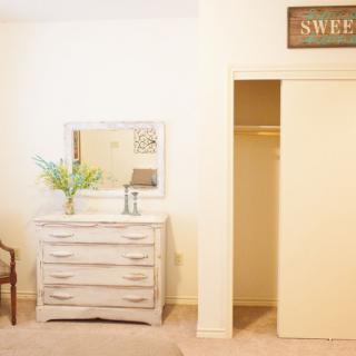 A minimalist bedroom with a dresser and mirror next to an open closet.