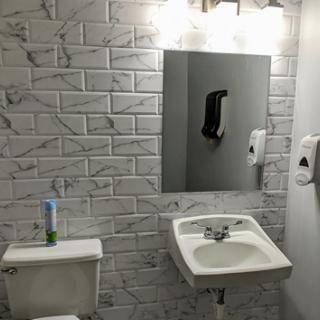 A modern bathroom setup featuring a sink, toilet, and mirror with lighting.