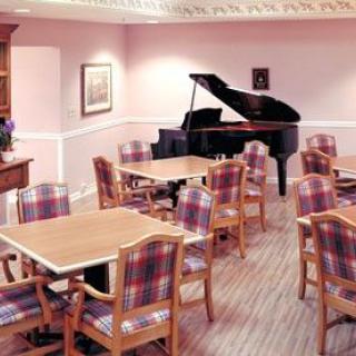 A cozy dining room with a grand piano and plaid-upholstered chairs.