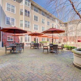 A cozy outdoor patio area with tables, chairs, and umbrellas in an apartment complex courtyard.