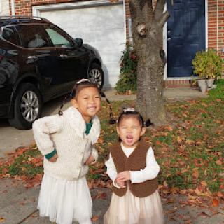 Two joyful children enjoying a sunny fall day outside their home.