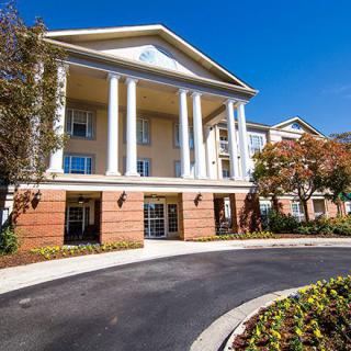 A residential building with classical columns and landscaped surroundings.