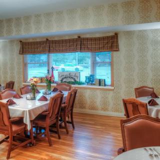 An elegant dining room with neatly arranged tables and chairs, featuring a large window with a view.