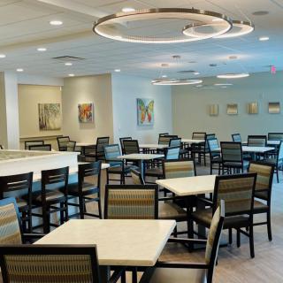 A modern dining area with empty tables and chairs, featuring contemporary lighting and wall art.