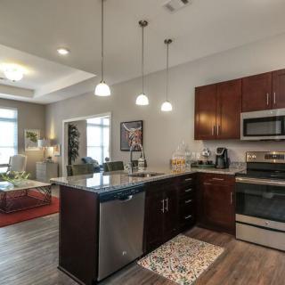 A modern kitchen with a central island, stainless steel appliances, and pendant lighting in an open floor plan setting.