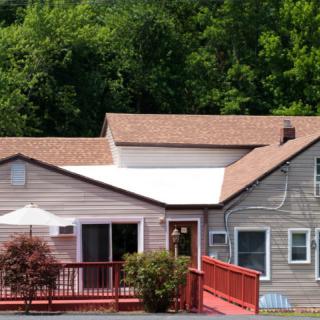 A quaint residential house with a red deck surrounded by lush greenery.