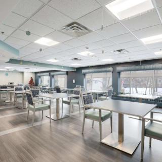 A modern, empty cafeteria with tables and chairs arranged under bright lighting.