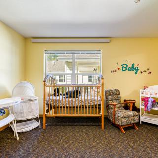 A cozy nursery with a crib, bassinet, rocking chair, and changing table.