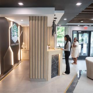 A modern hotel lobby with two people checking in at the reception desk.
