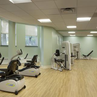 A well-lit gym with various exercise machines and equipment.