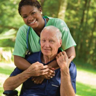 A caregiver and an elderly man enjoying time outdoors.