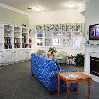 A cozy living room with a blue sofa, fireplace, and a television mounted above it.