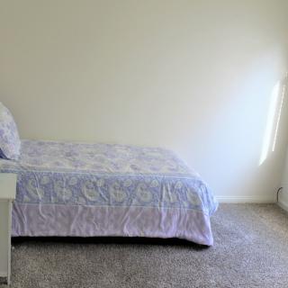 A minimalist bedroom with a bed and natural light coming through the window.