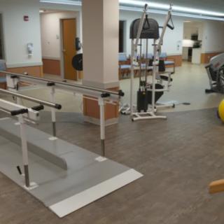 A rehabilitation center with parallel bars and gym equipment.