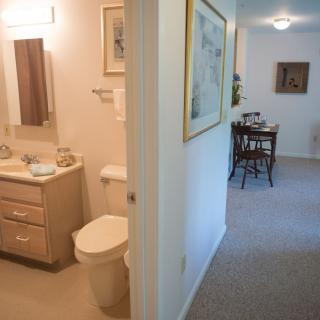 A view of a bathroom and adjoining hallway leading to a dining area.