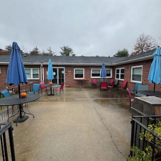A cozy outdoor patio area with blue umbrellas and seating, set against a cloudy sky.