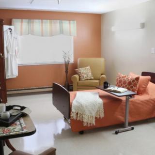 A well-furnished hospital room with a bed, chair, and table.
