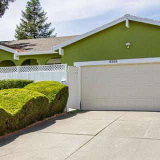 A green suburban house with a driveway and a garage.