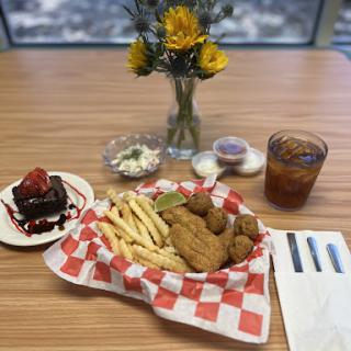 A delicious meal featuring fried chicken and fries, accompanied by a chocolate dessert and fresh flowers.