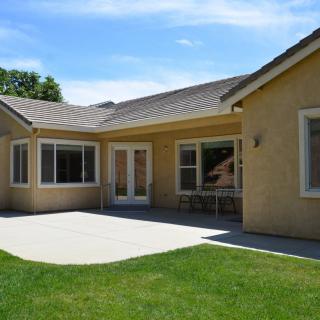 A single-story house with a patio and green lawn.