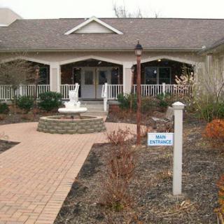A charming building surrounded by landscaped gardens and a decorative fountain.