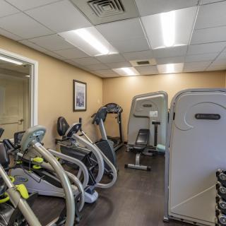 A small gym with various exercise equipment, including treadmills and elliptical machines.