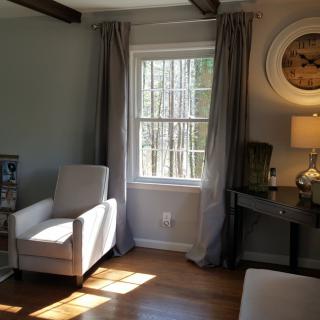 A cozy living room with an armchair by the window, illuminated by natural light.