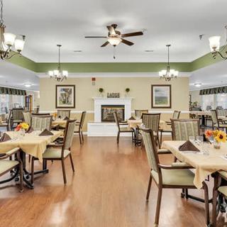 An elegant dining room with multiple tables and chairs, decorated with warm lighting.