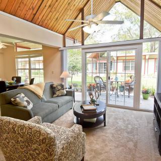 A cozy living room featuring a wooden ceiling and large windows overlooking an outdoor space.