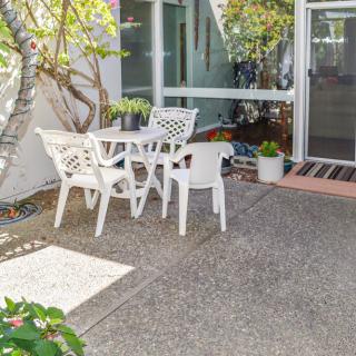 A sunny patio with white outdoor furniture set among greenery.