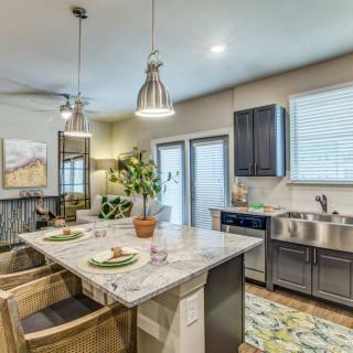 A modern kitchen with an island counter and pendant lighting, featuring stainless steel appliances and an open layout.
