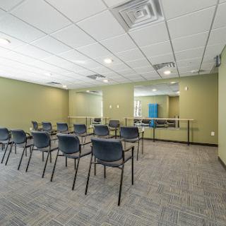 A spacious and empty meeting room equipped with chairs, featuring green walls and a professional atmosphere.