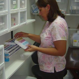 A nurse organizing medical supplies in a storage room.
