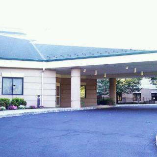 The image depicts the exterior entrance of a building with a covered driveway and columns.