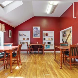 A quiet library study area with red walls and wooden floors, featuring tables, chairs, and bookshelves.