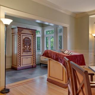 A cozy room with a bed, wooden cabinet, and floor lamps next to large windows.