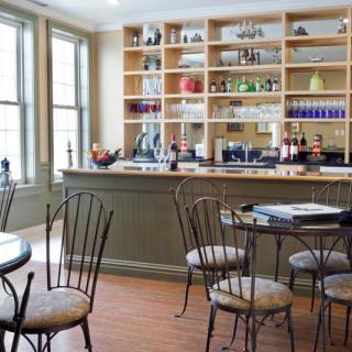 A cozy cafe interior with metal chairs, round tables, and a well-stocked bar.